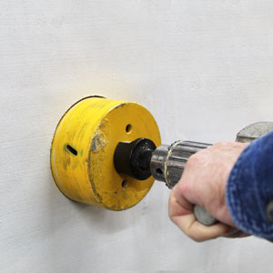 Photo of wall hole for Condar passive air supply ventilator being drilled